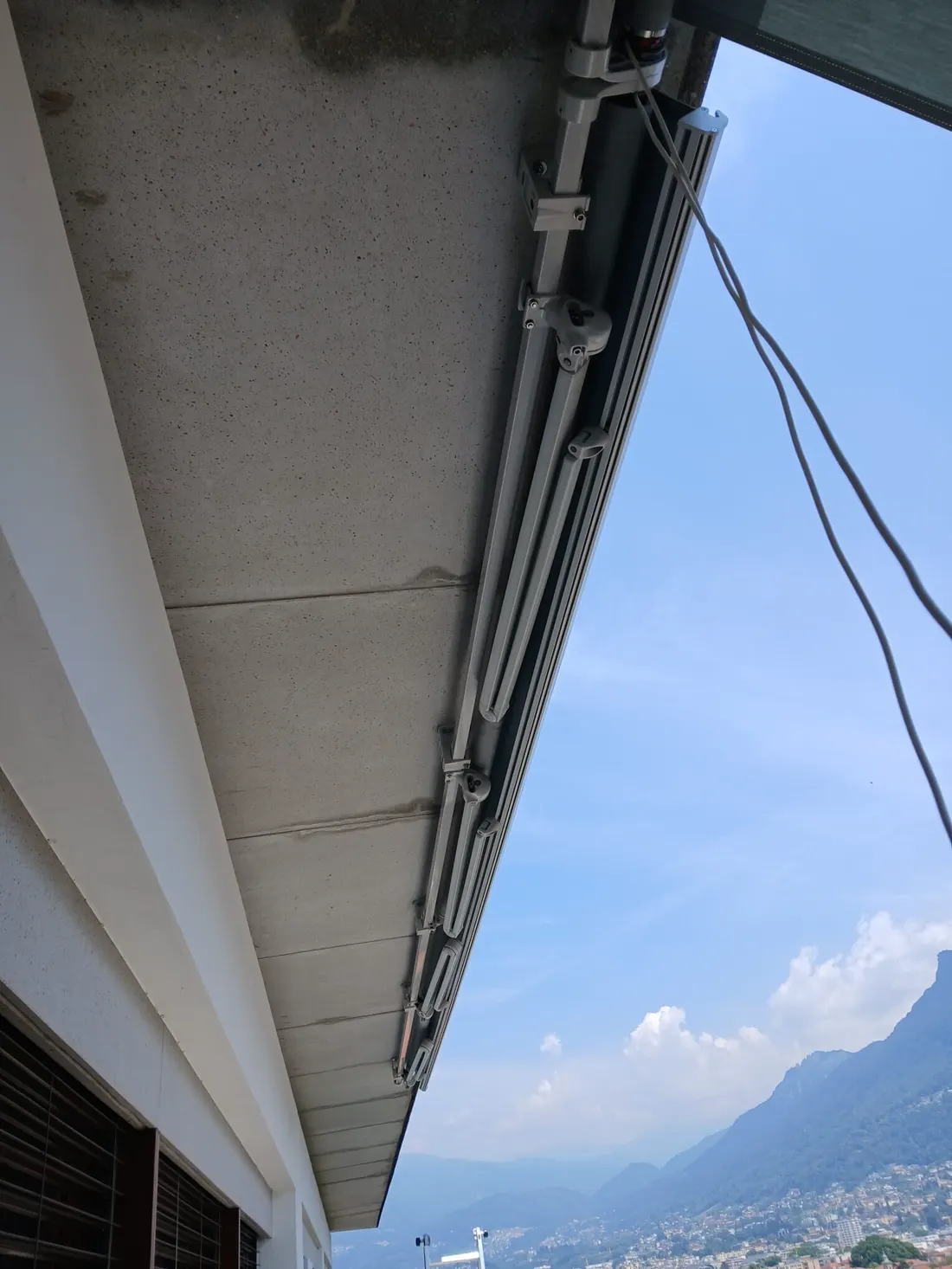 Braccio e cassonetto di una tenda appena montata, lago sullo sfondo