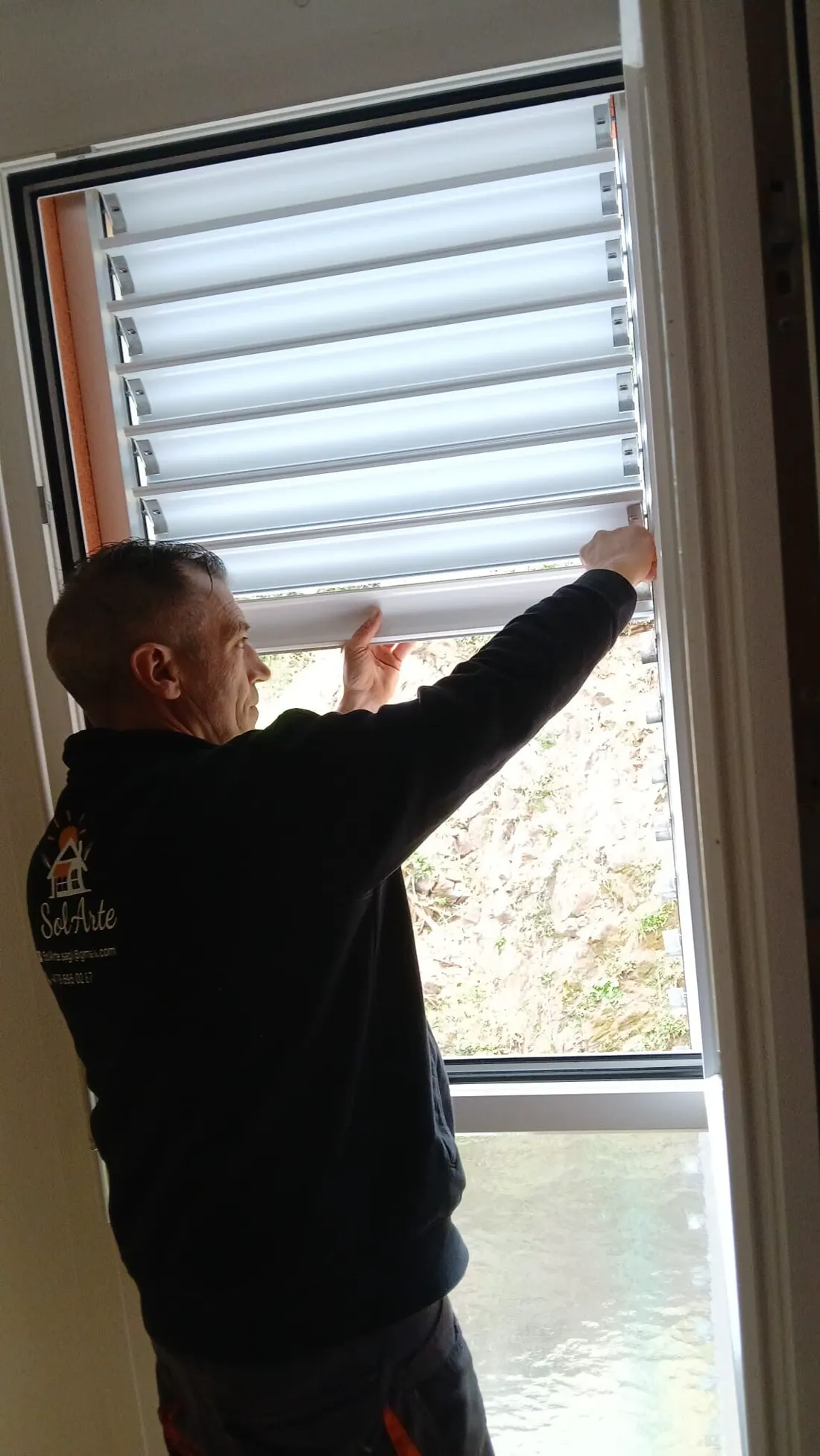 Un posatore con la giacca SolArte regola le lamelle di una finestra